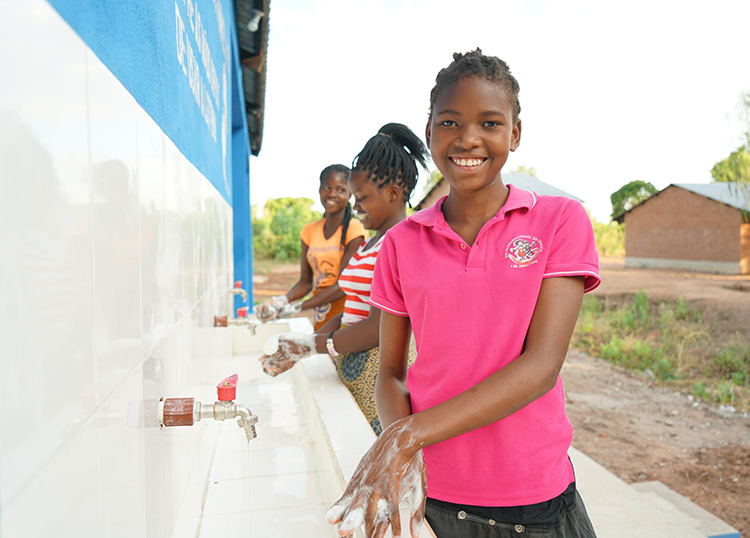 Madina is happily using newly installed hand wash apparatus at school. (Mozambique)