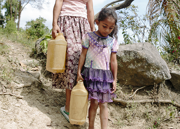 Rosalie and her daughter Laura (aged 5) walking on a rough road to draw water (East Timor)