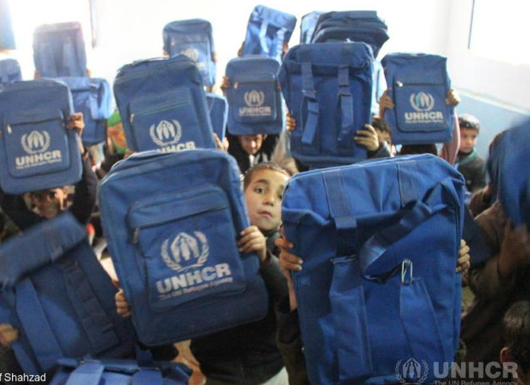 パキスタンにて、UNHCRの学校用バッグを見せてくれるアフガン難民の子どもたち